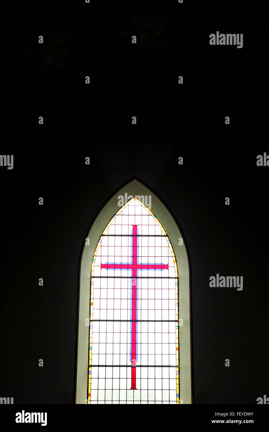 Atmosphärische, dunkel und schönen Fleck Glas Kirchenfenster mit einem Kreuz in Irland Stockfoto