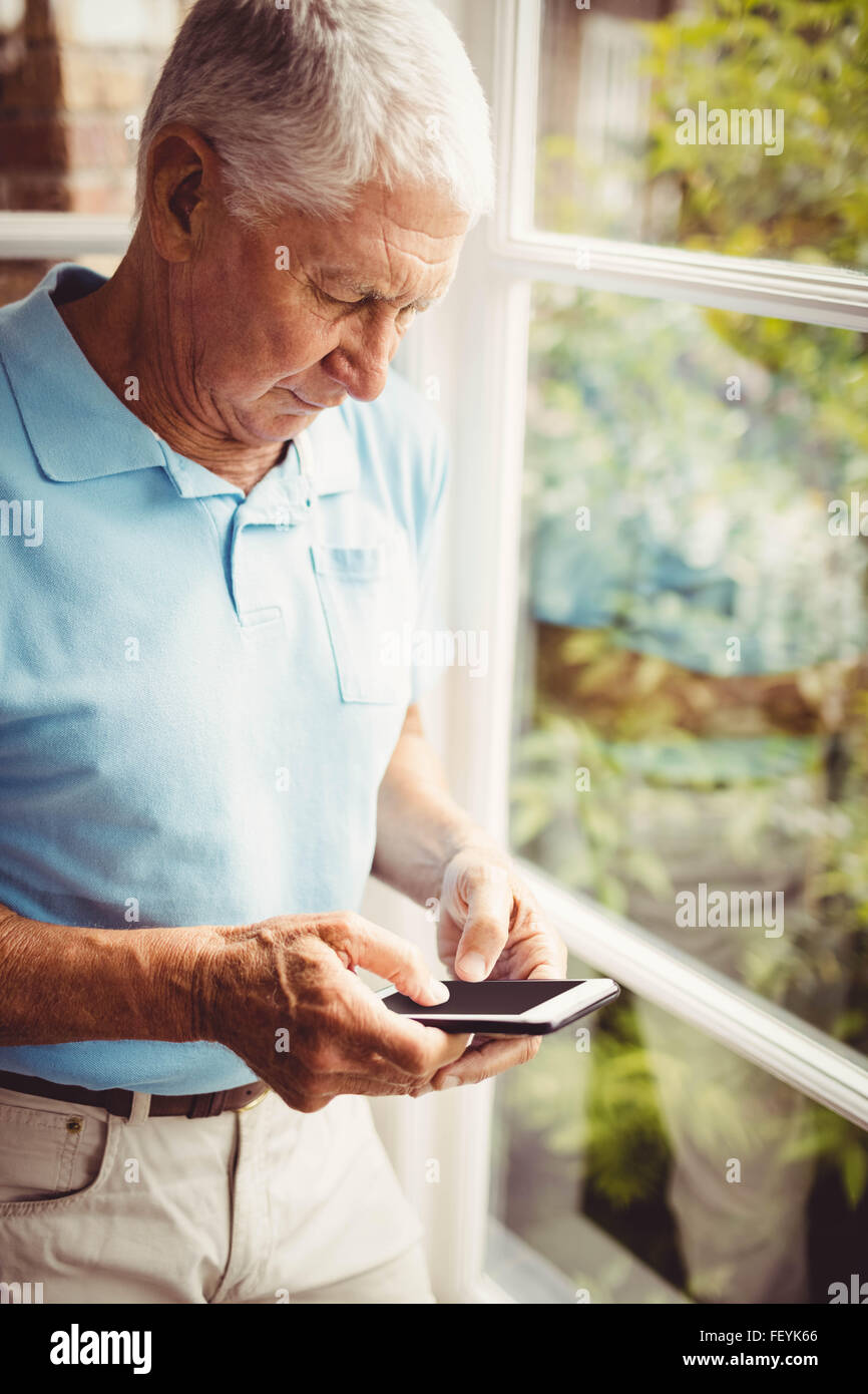 Ältere Mann neben dem Fenster mit smartphone Stockfoto