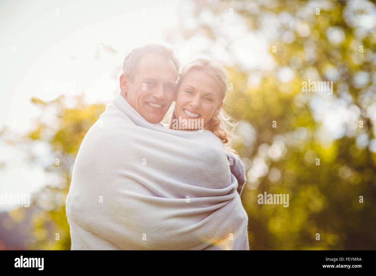 Nettes Paar mit einer Decke um umarmt Stockfoto
