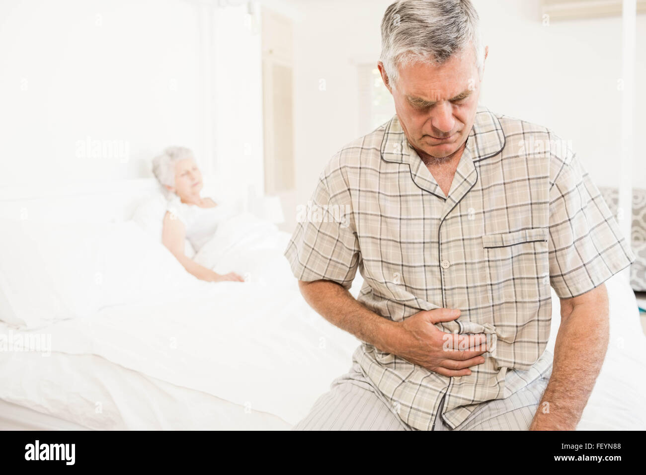 Ältere Mann, der seinen Bauch leiden Stockfoto