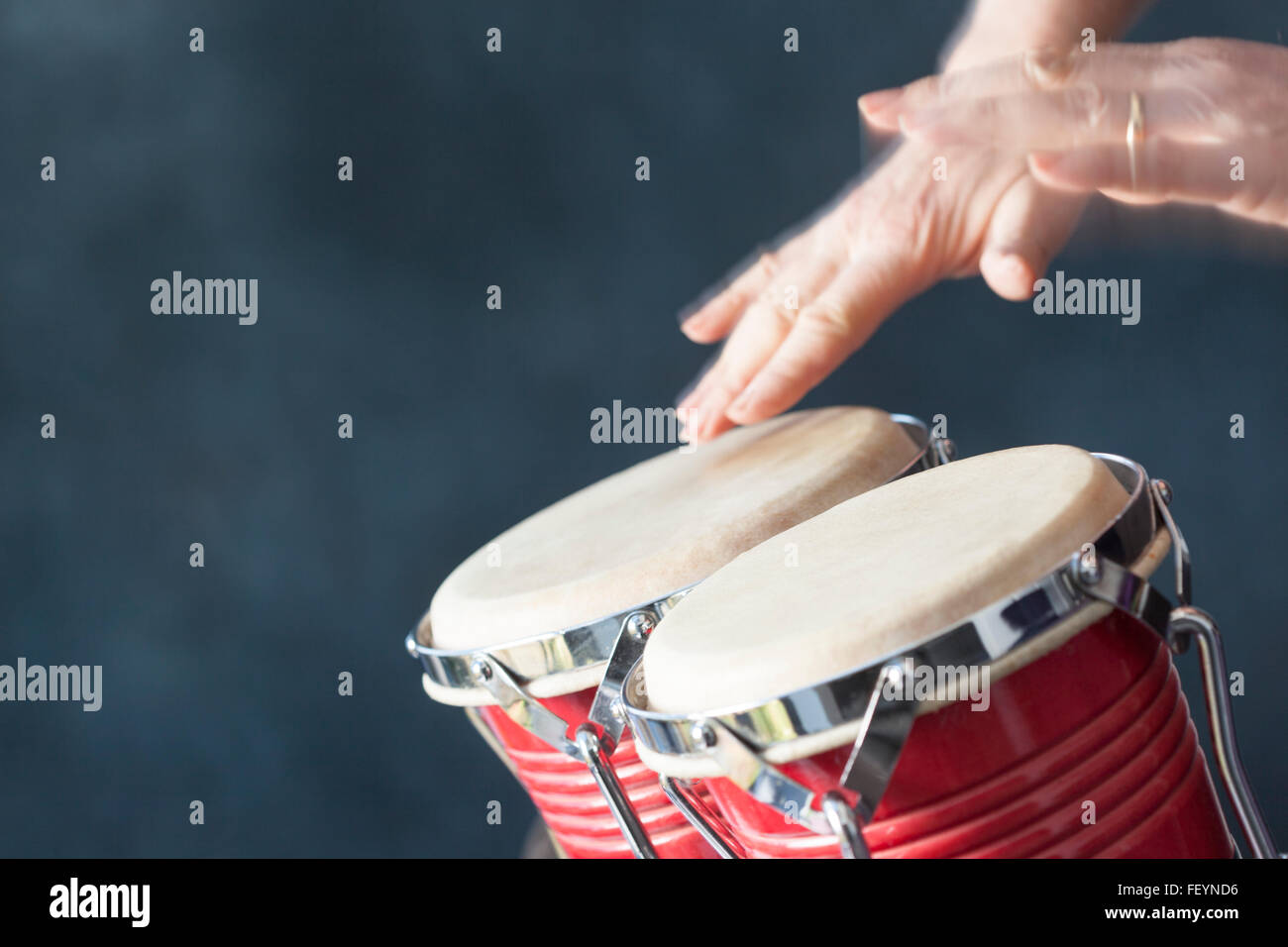 Hände spielen rote Bongo-Trommeln mit grauem Hintergrund Stockfoto