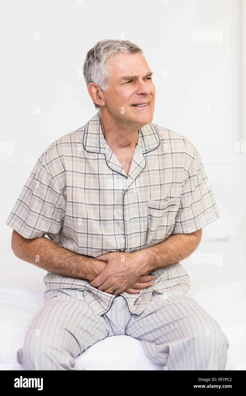 Ältere Mann, der seinen Bauch leiden Stockfoto