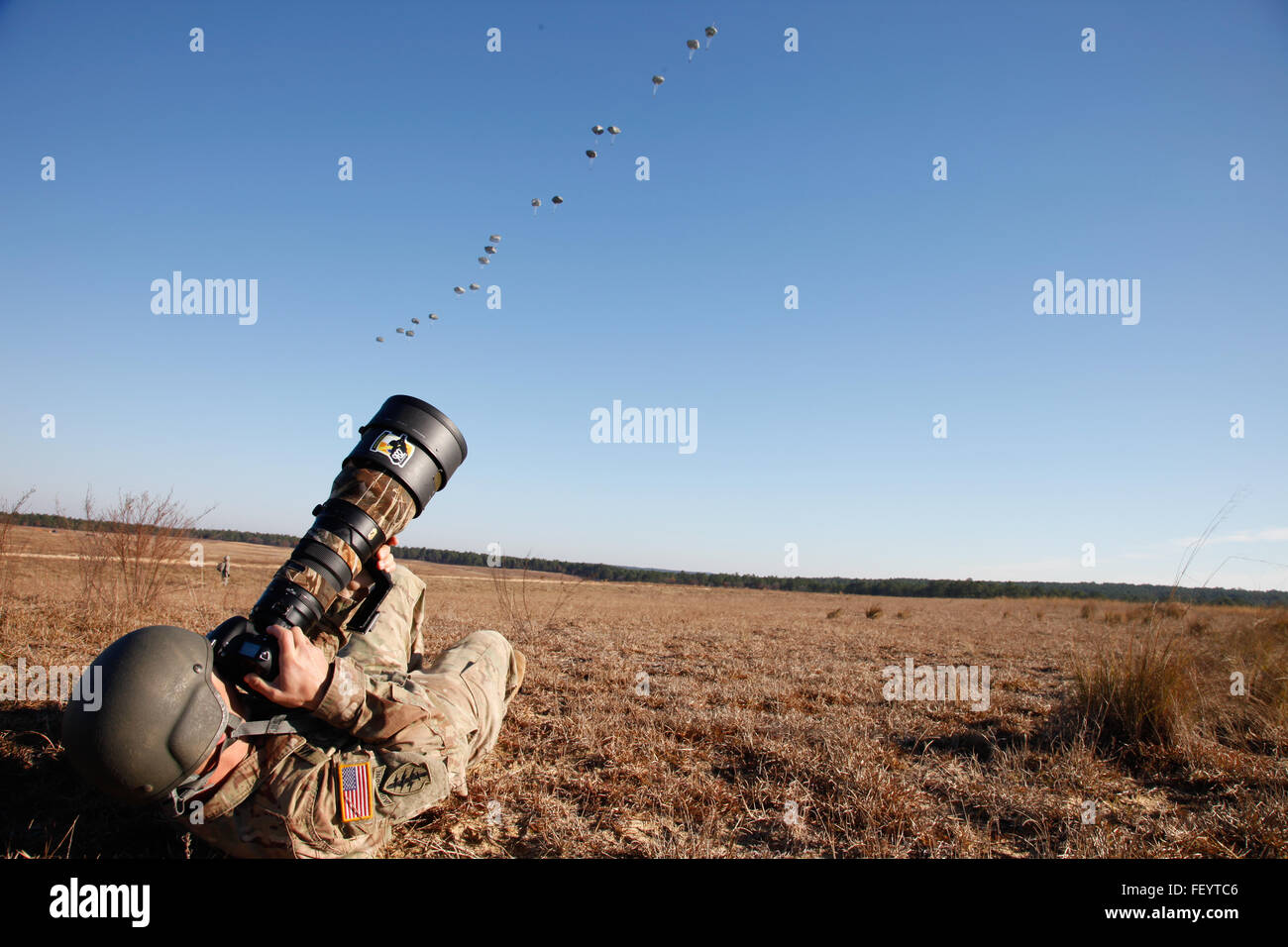 US Army Staff Sgt Alex Manne, zugewiesene 982nd Combat Camera Company, dokumentiert US Army Fallschirmjäger landen auf Sizilien-Drop-Zone während der Operation in der Luft für die 18. jährliche Randy Oler Memorial Betrieb Spielzeug fallen, moderiert von US Armee zivile Angelegenheiten & psychologische Operations Command (Airborne), in Fort Bragg, N.C., 4. Dezember 2015. Betrieb Spielzeug Drop ist der weltweit größte zerstreute Betrieb und kollektive Training kombiniert mit sieben teilnehmenden Partner-Nation-Fallschirmjäger und Soldaten die Möglichkeit zu helfen, Kinder in Not Spielzeug für den Urlaub erhalten. Stockfoto