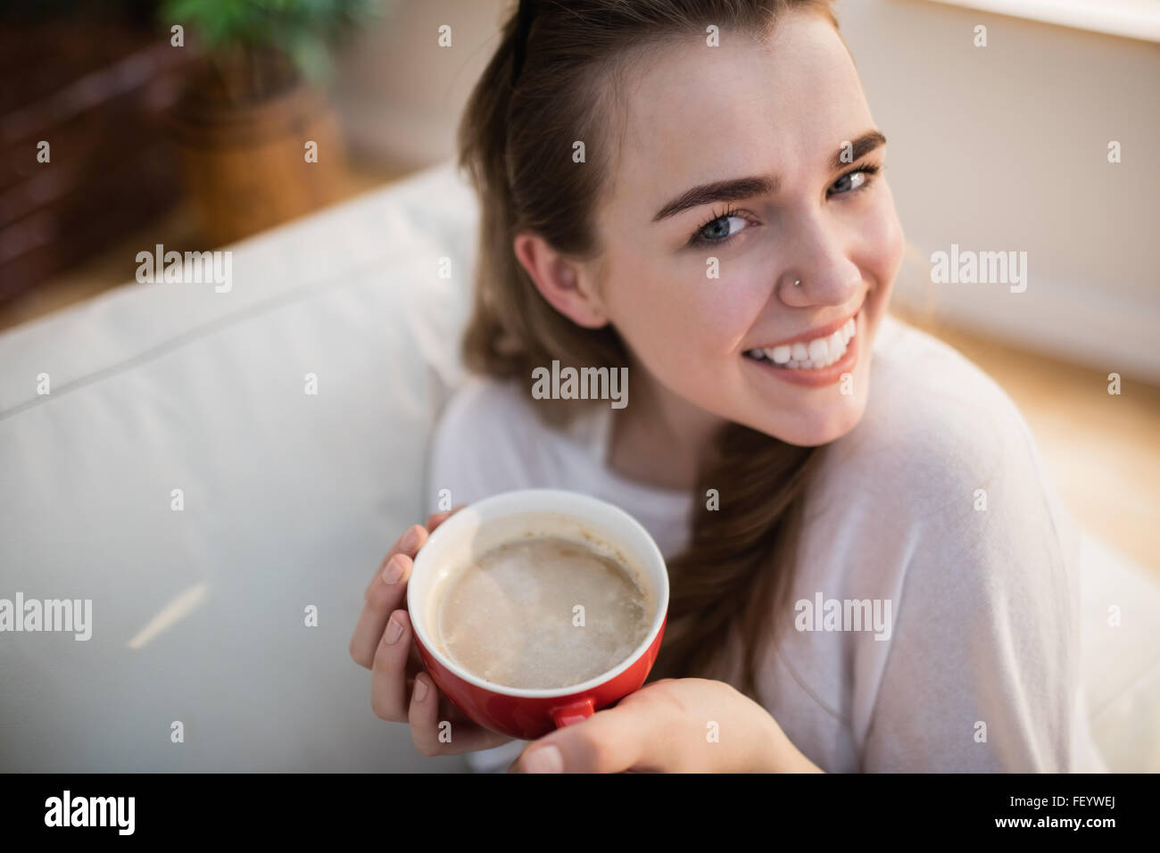 Hübsche Frau entspannend auf Couch mit Kaffee Stockfoto