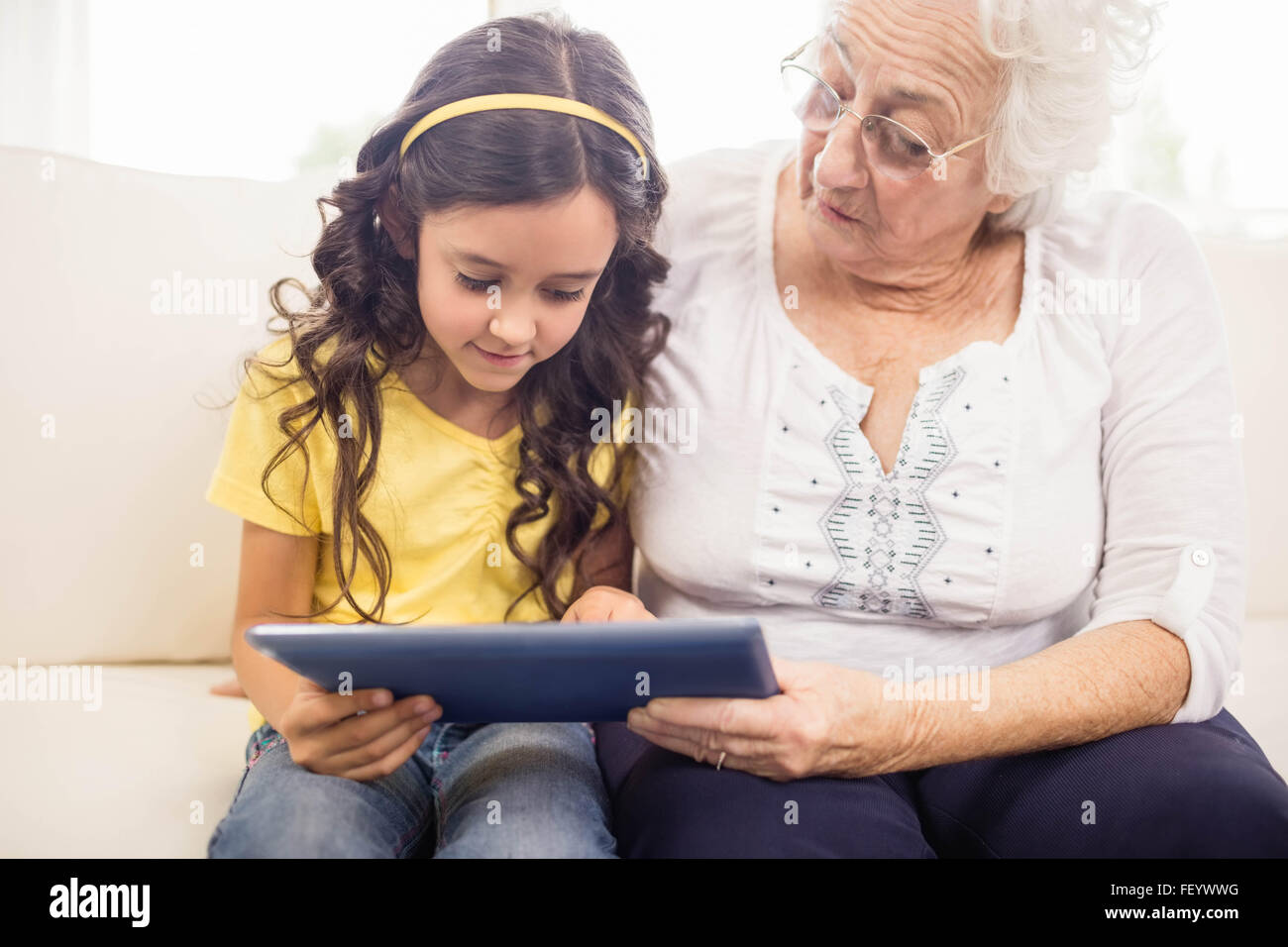 Konzentrierte Enkelin mit Tablet mit Großmutter Stockfoto