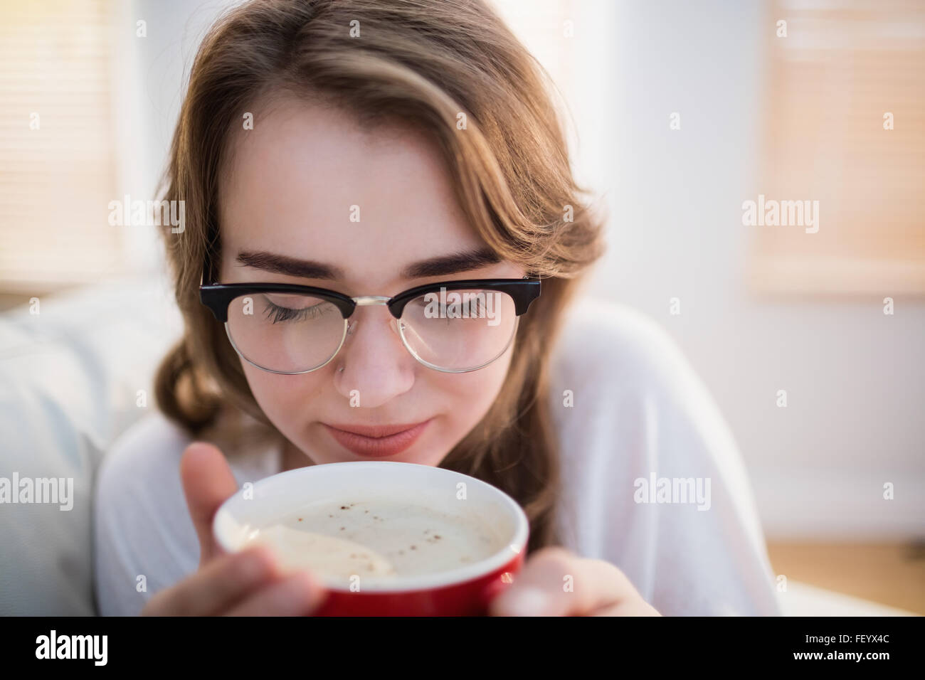 Hübsche Frau entspannend auf Couch mit Kaffee Stockfoto