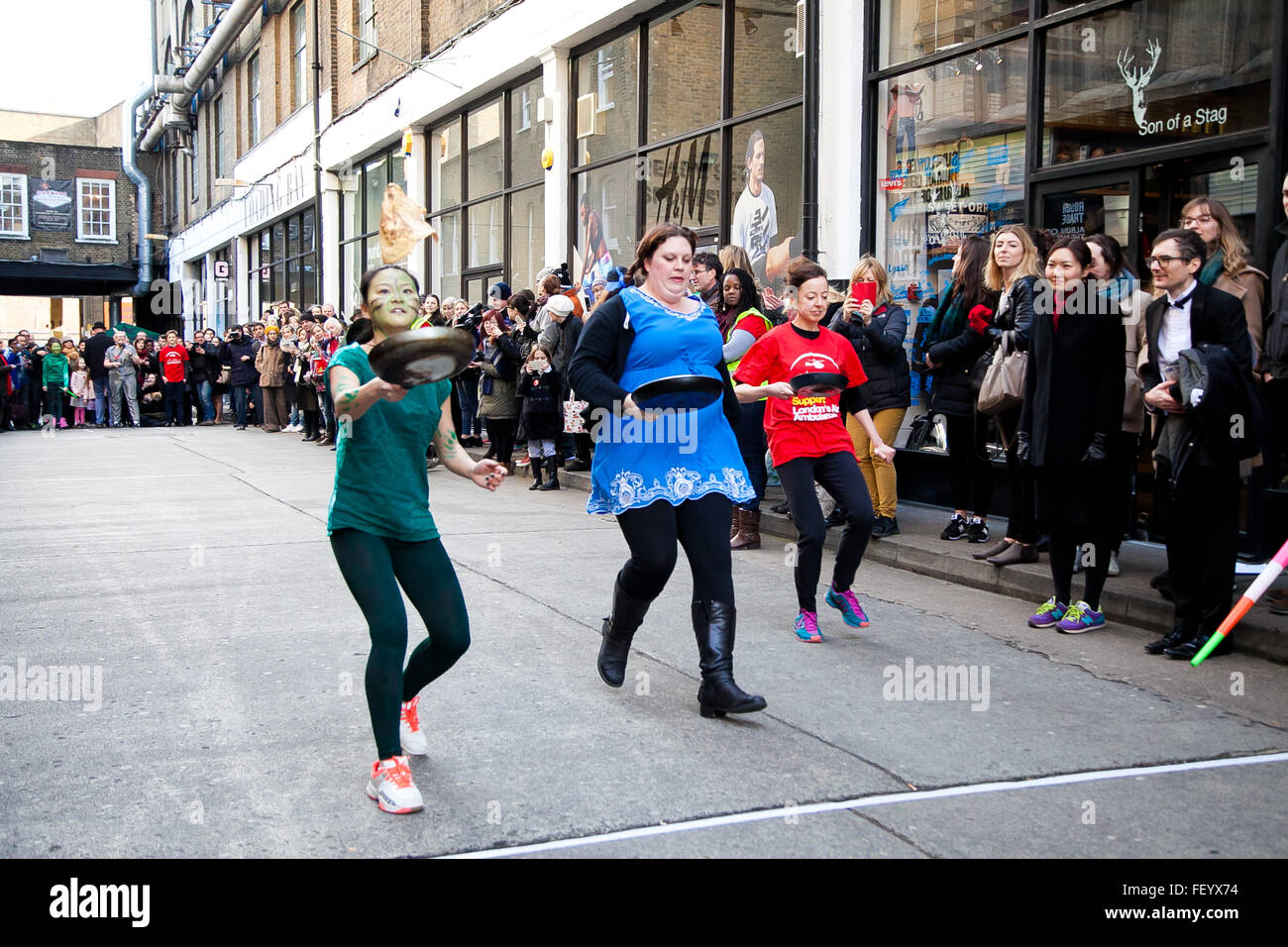 London, UK. 9. Februar 2016. Teilnahme an The Great Spitalfields Pancake Race am Faschingsdienstag an der Old Truman Brewery in East London. 4 Mannschaften, für die Ehre des Werdens der diesjährigen Champions, während das Ereignis Mittel für Londoner Air Ambulance auslöst Stockfoto