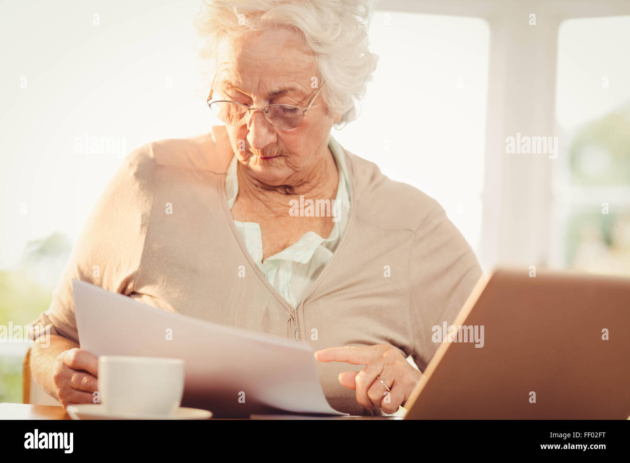 Ältere Frau Umgang mit Dokumenten während mit laptop Stockfoto