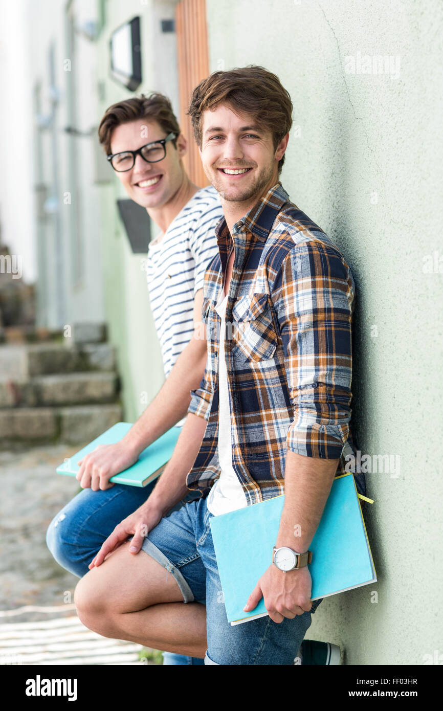 Angesagte Männer Wand gelehnt und hält Notizbücher Stockfoto