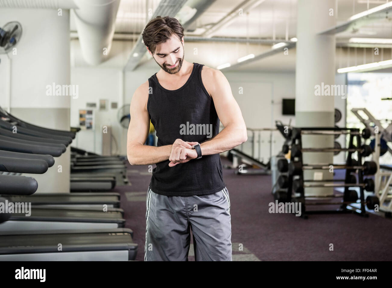 Lächelnder Mann auf Laufband Smartwatch betrachten Stockfoto