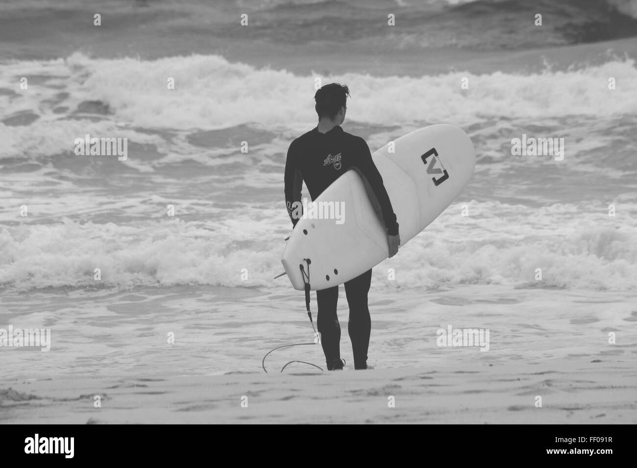 Strand menschlichen Monochrom Ocean Shore Surfbrett Surfer Flut Wasser Neoprenanzug schwarz und weiß im freien Person stehende Wellen zum Surfen Stockfoto