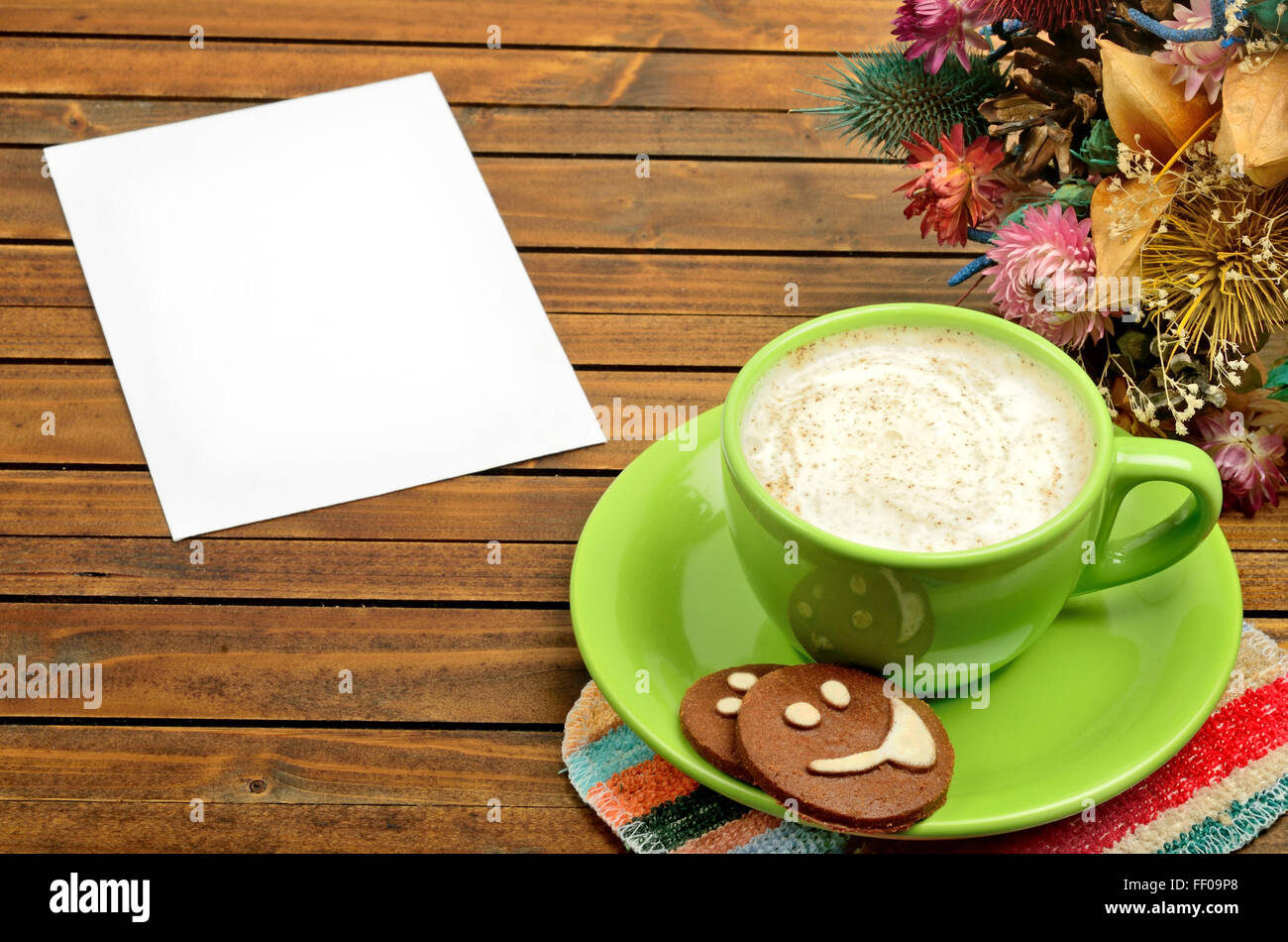 Tasse Cappuccino mit leeren Papier auf Holztisch Stockfoto