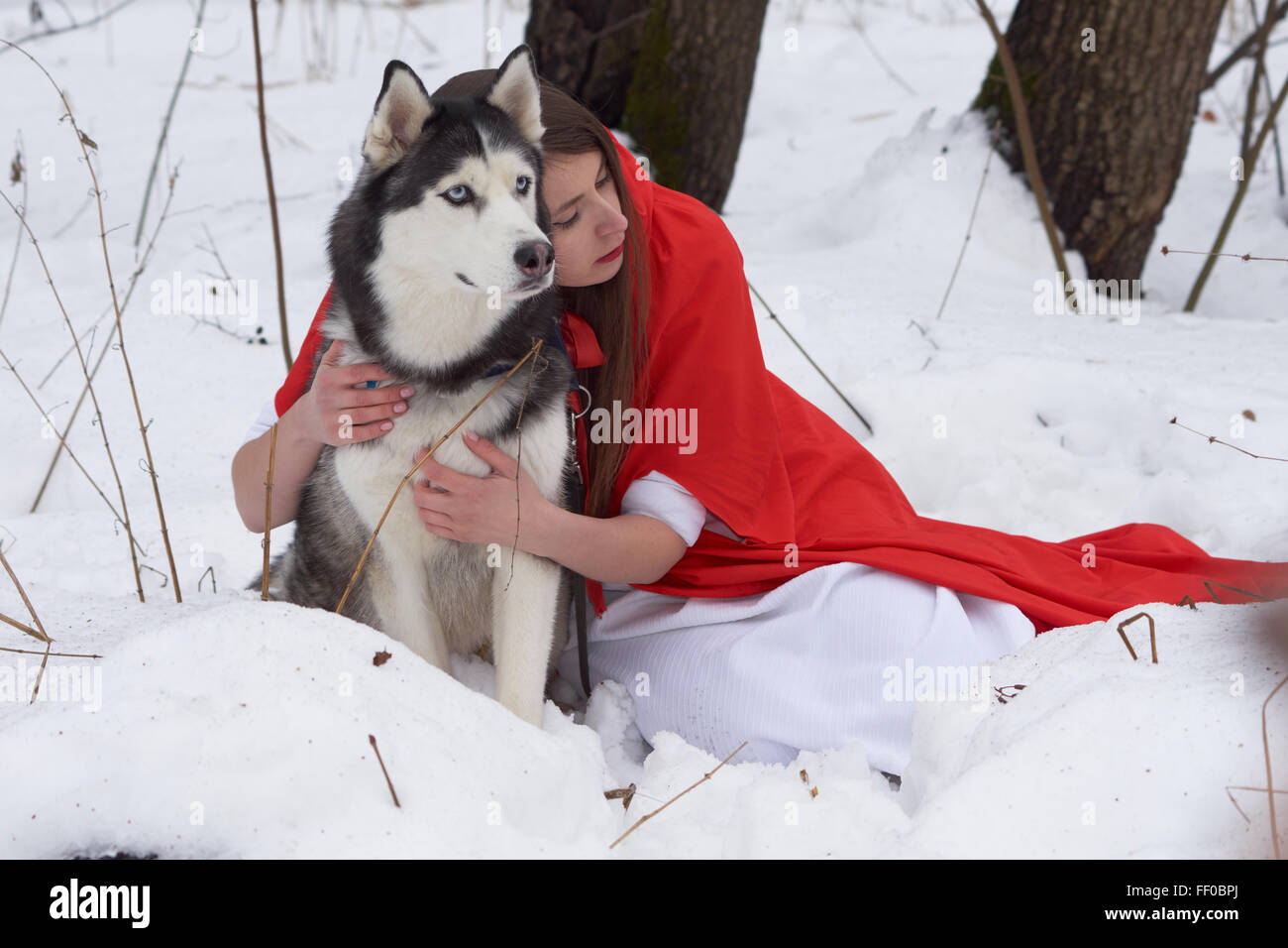 Mädchen im roten Umhang mit Siberian Husky Stockfoto