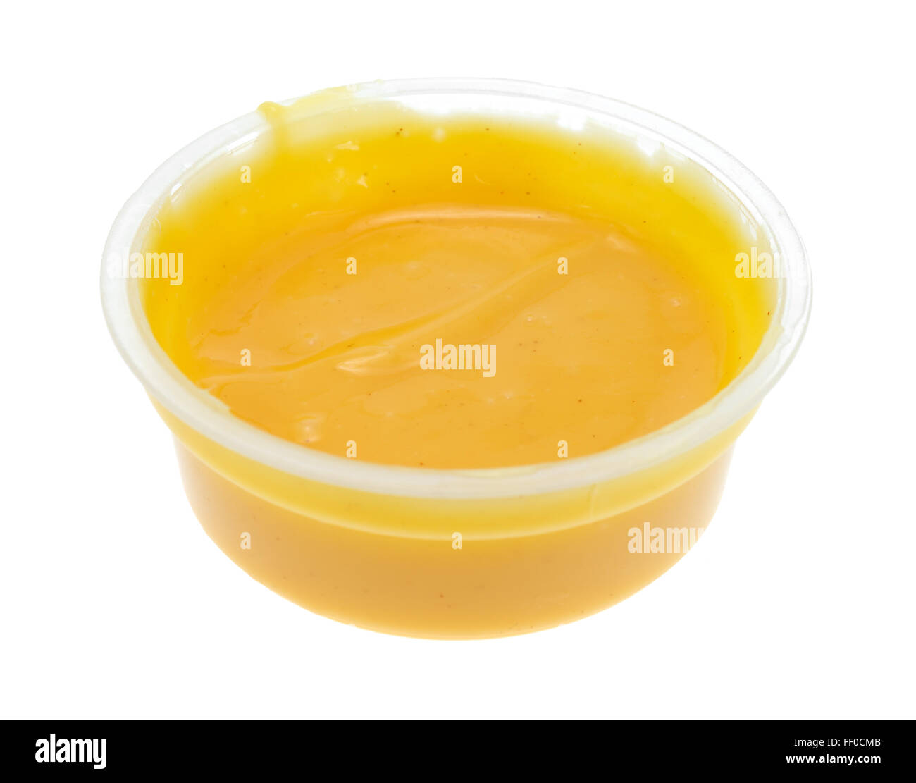 Seitlicher Blick auf einen kleinen Behälter mit Honig-Senf Salatdressing isoliert auf einem weißen Hintergrund. Stockfoto