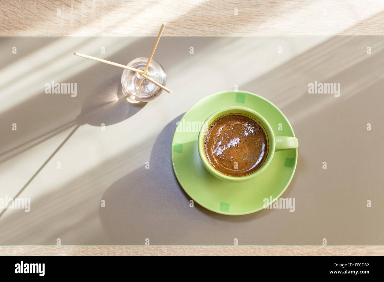 grüne Tasse Kaffee und Weihrauch steckt in natürlichem Licht Stockfoto