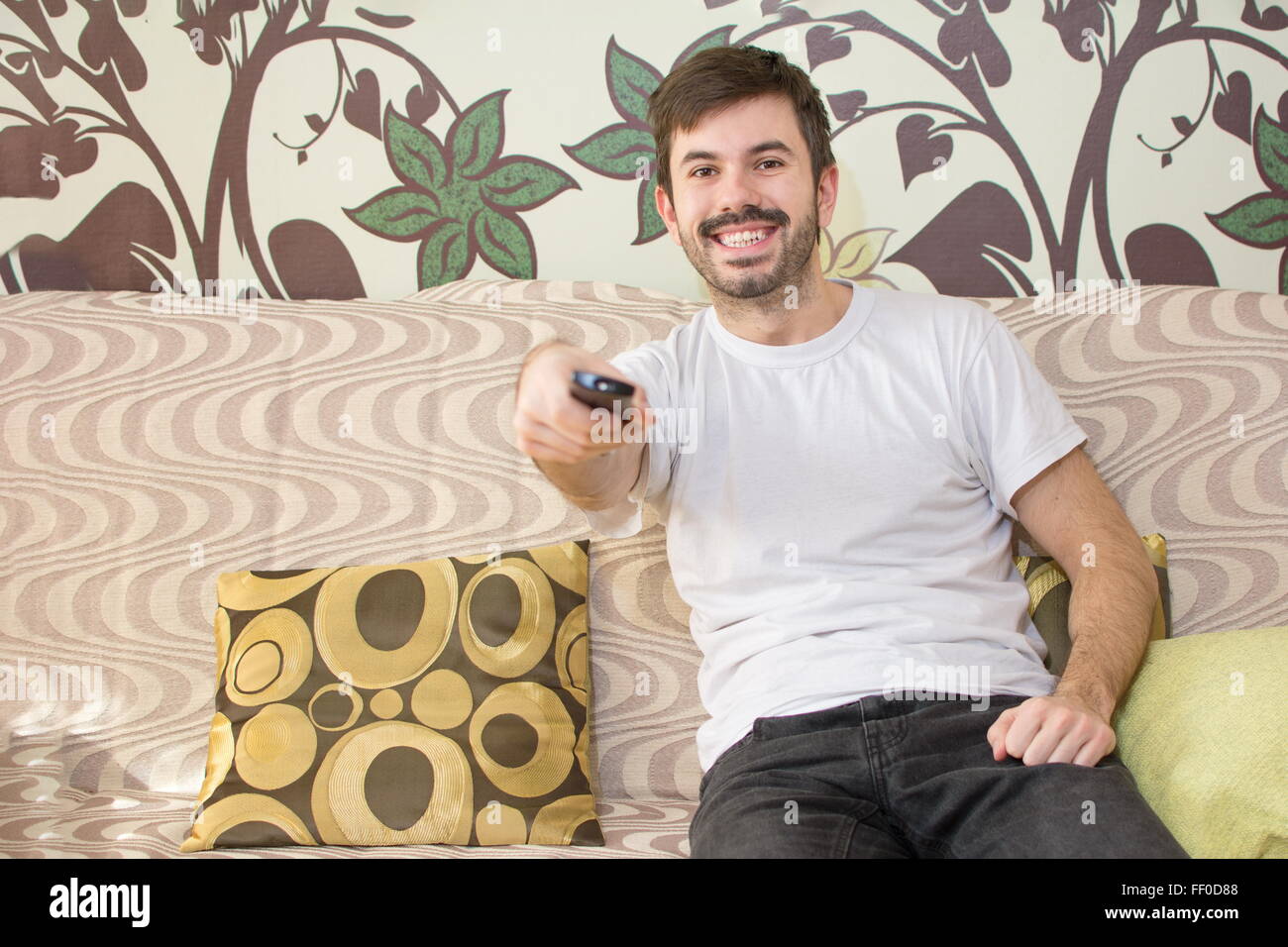 bärtiger Mann mit einer Fernbedienung auf einem sofa Stockfoto