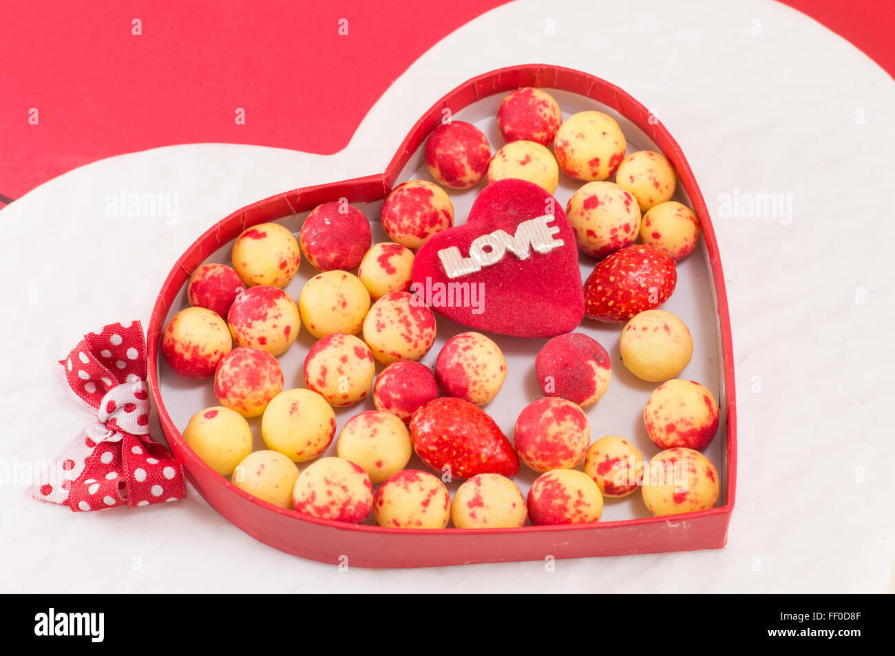 Box mit roten und gelben Süßigkeitsbälle in Herzform Stockfoto