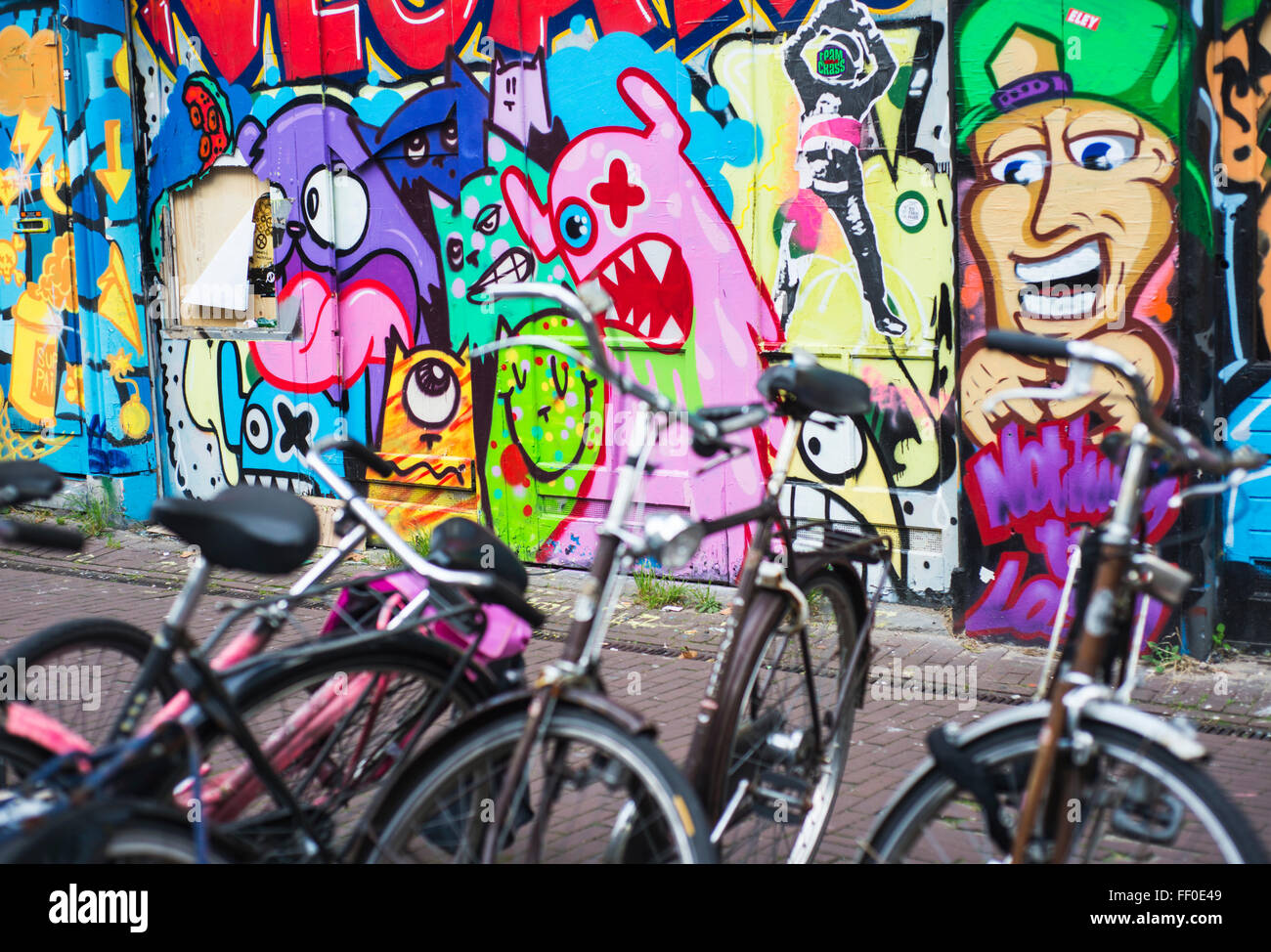 Geparkte Fahrräder vor einer Wand voller graffiti Stockfoto