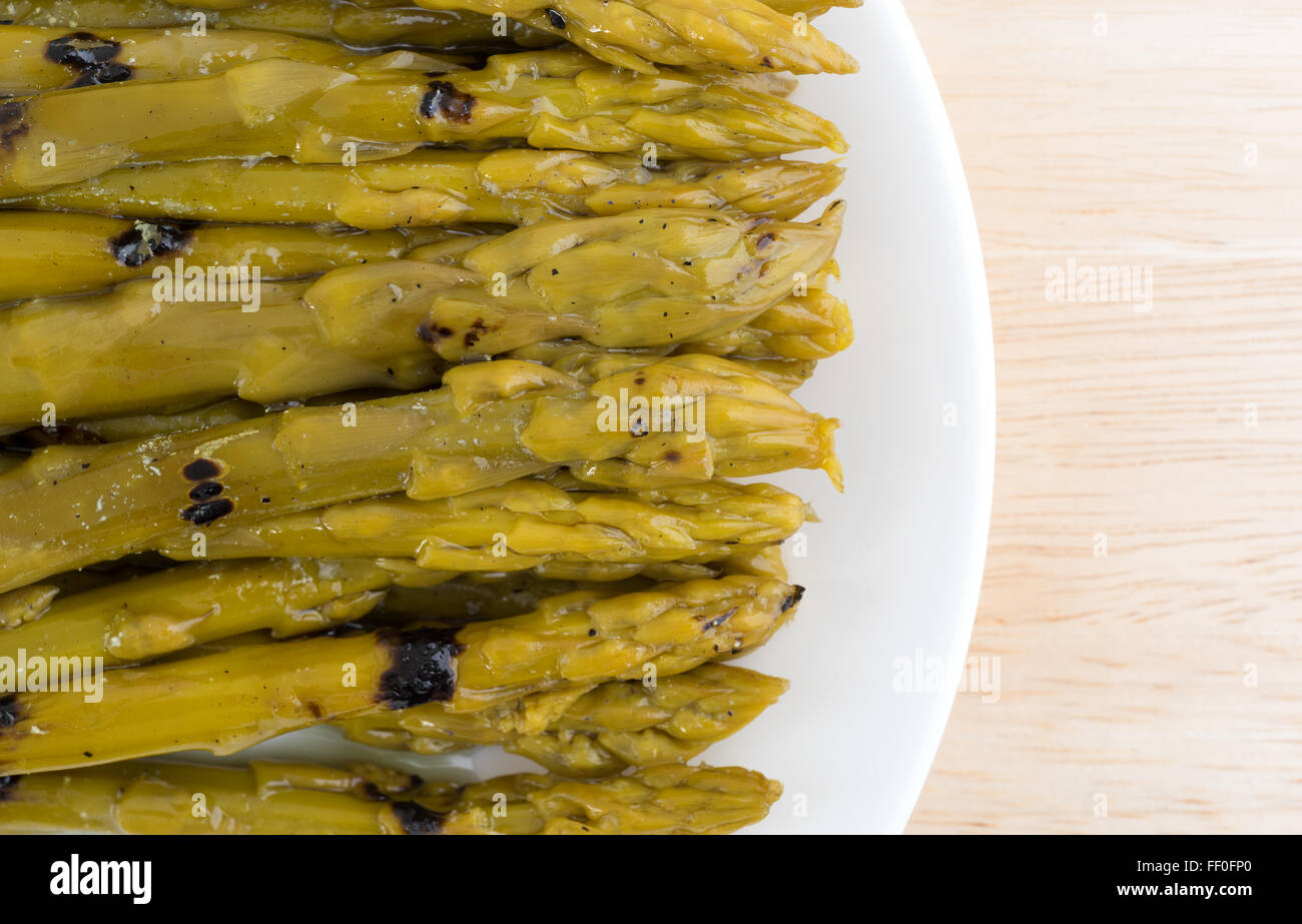 Eine Top in der Nähe Blick auf gegrillter Spargel getränkt in Sonnenblumenöl auf einem Holztisch mit natürlichem Licht beleuchtet. Stockfoto