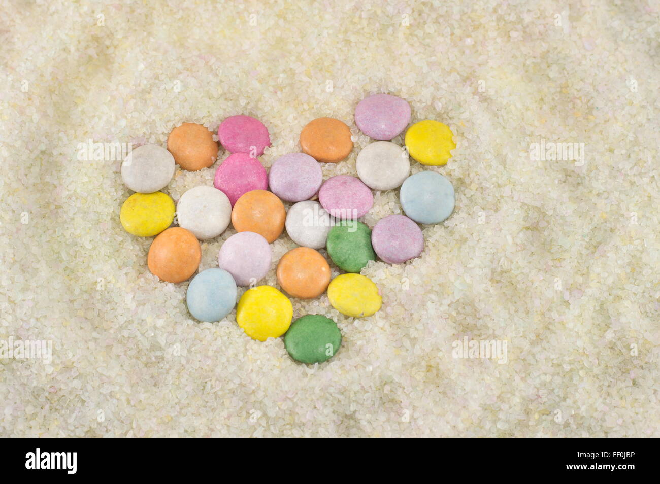 bunte Bonbons angeordnet, um ein Herz in Zucker zu machen Stockfoto