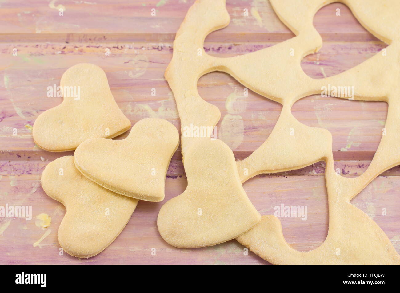 Teig mit Herzen Ausschneiden auf einem Holztisch Stockfoto