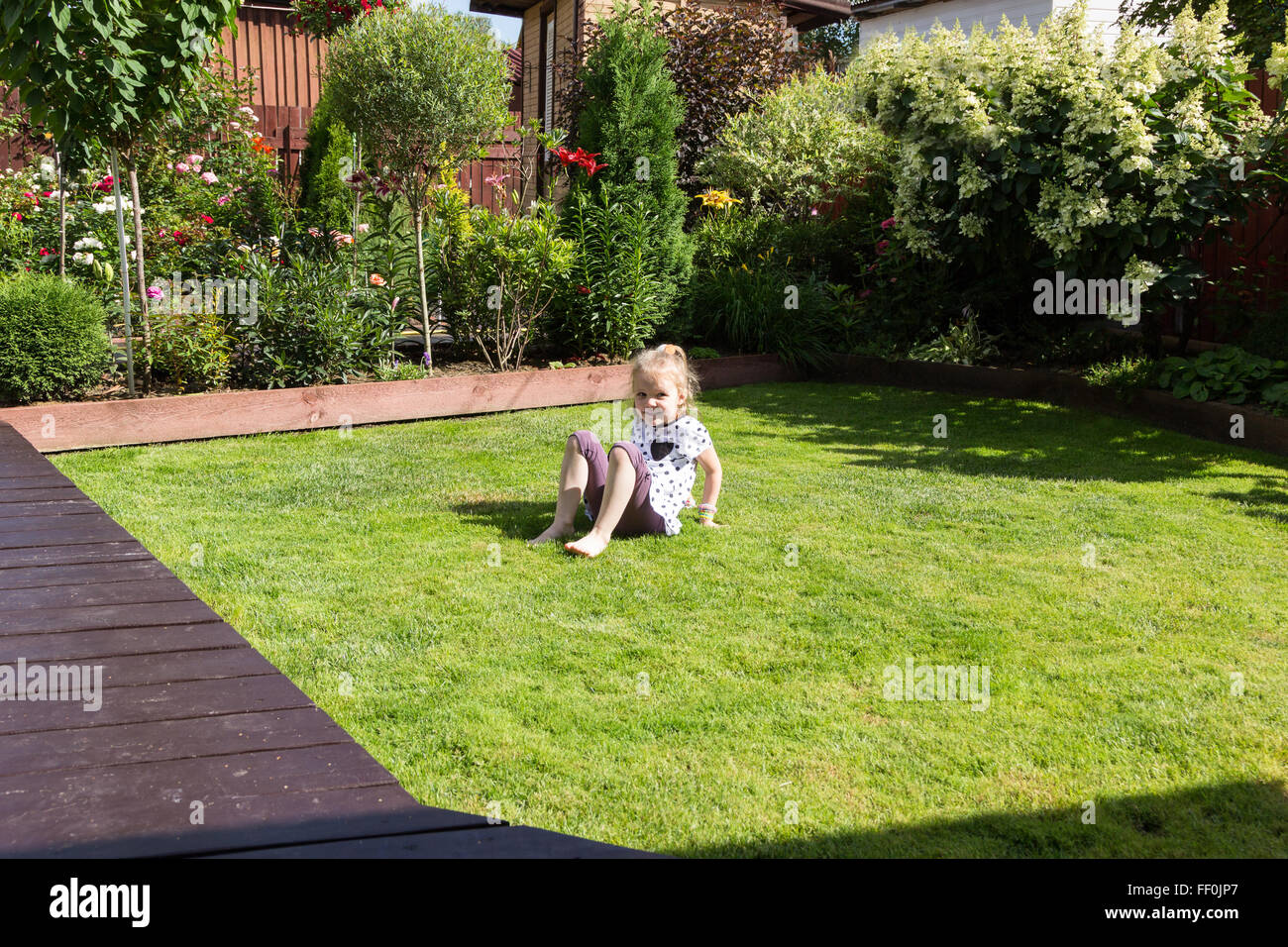 Mädchen spielen auf Rasen in einem schönen Garten Stockfoto