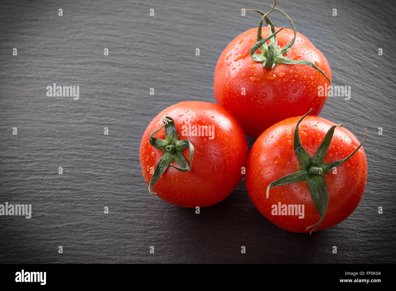 Tomaten auf einem dunklen Stein Hintergrund. Stockfoto