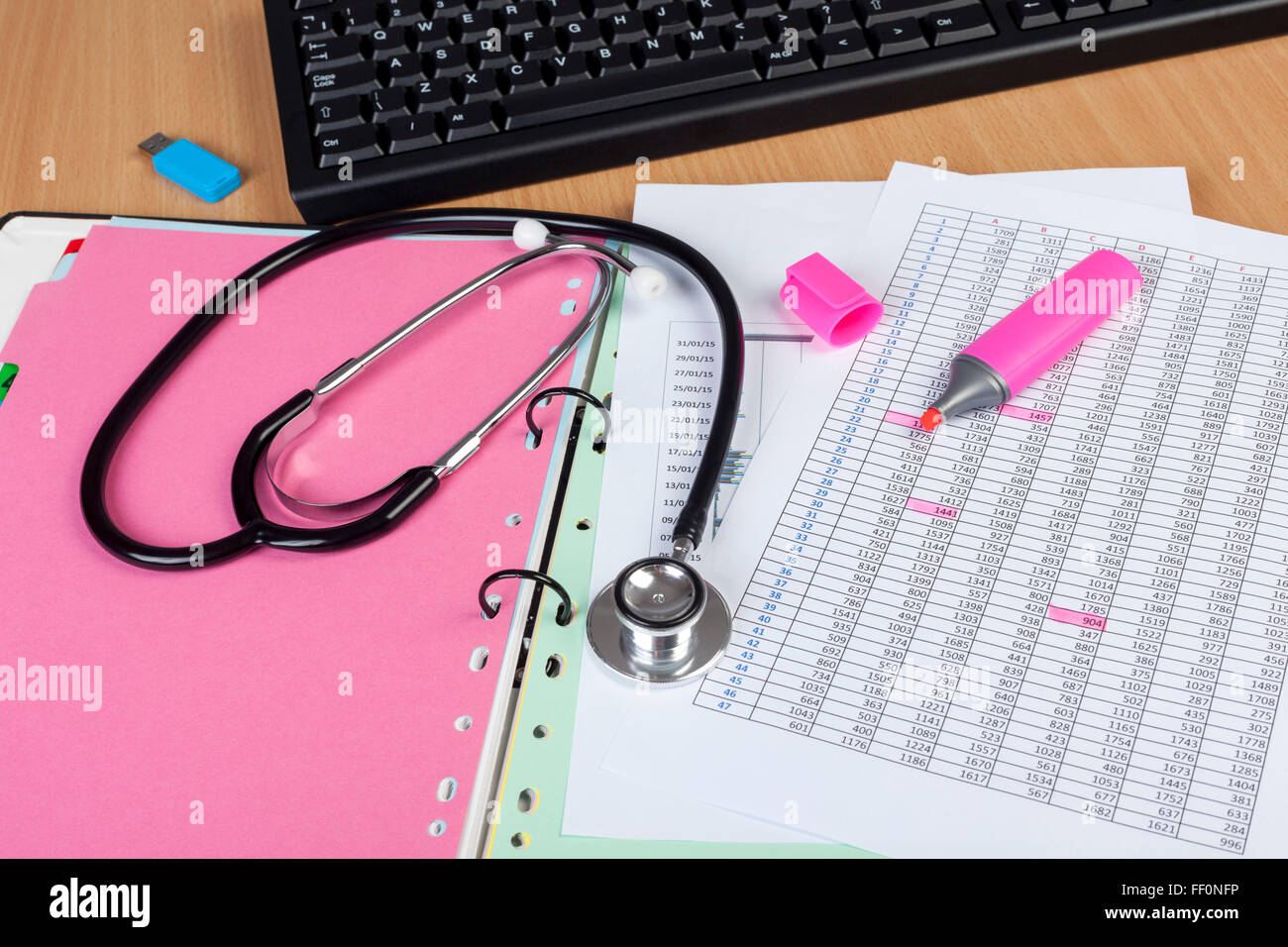Medizinisches Personal Desktop zeigt ein Stethoskop, Computertastatur und einige finanzielle Berichte in einem Ordner Stockfoto