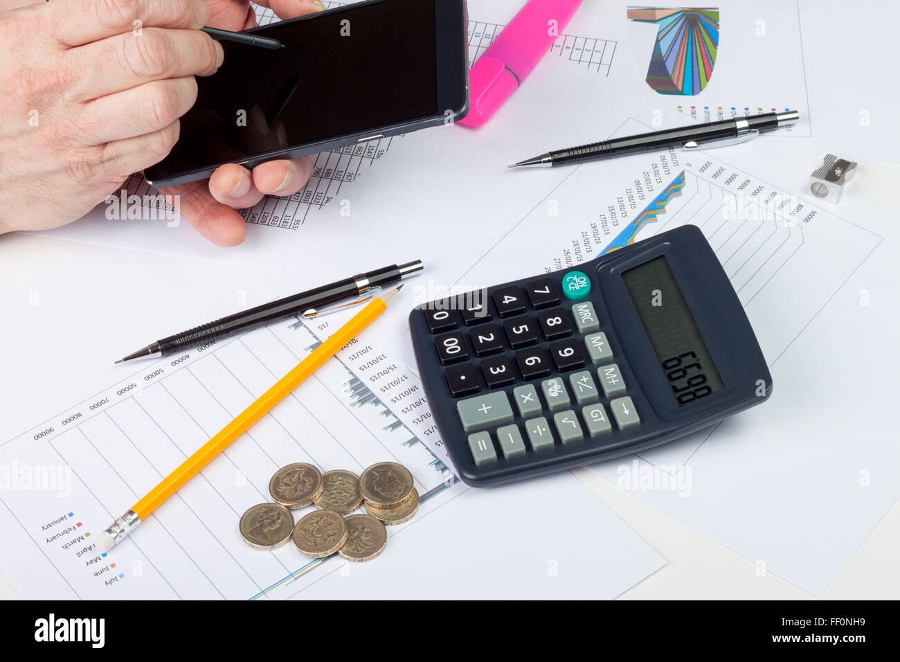 Beschäftigt Buchhalter bei der Arbeit mit seinem Smartphone mit Bargeld und Acalculator auf seinem Schreibtisch Stockfoto