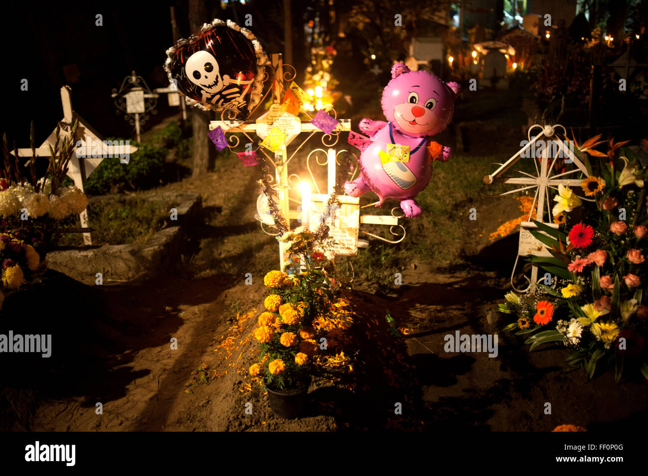 Ein Teddybär-Ballon in einem Grab mit Blütenblättern und gelben Ringelblumen, bekannt als cempasuchil Stockfoto