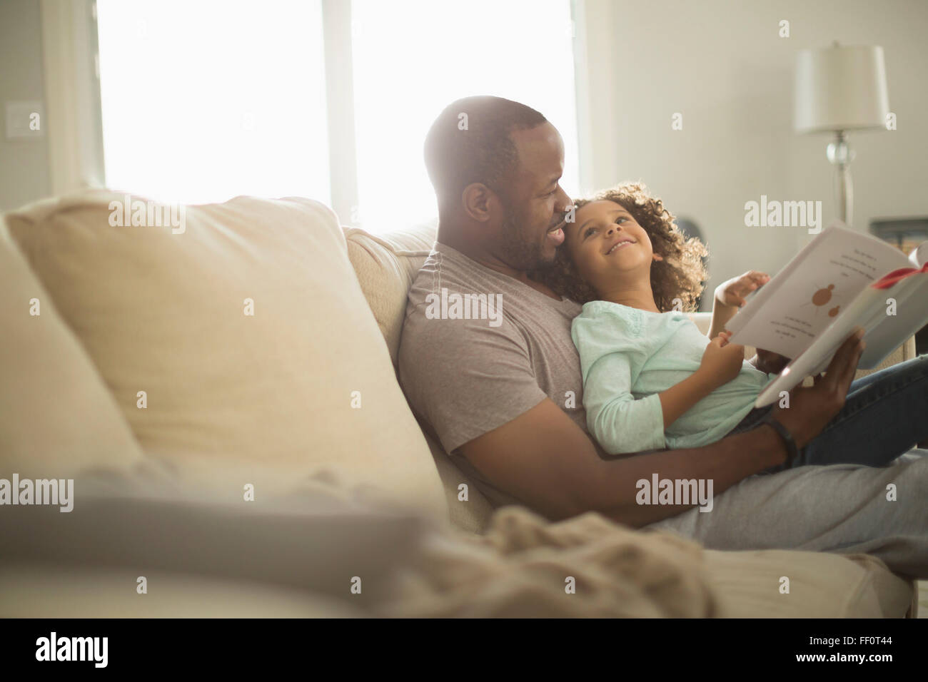 Vater und Tochter auf Sofa lesen Stockfoto