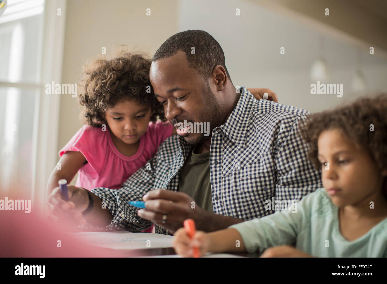 Vater und Töchter zeichnen am Tisch Stockfoto