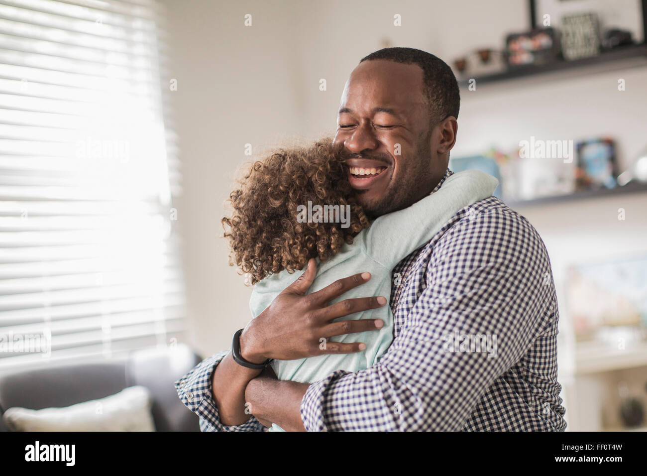 Vater und Tochter umarmt im Wohnzimmer Stockfoto