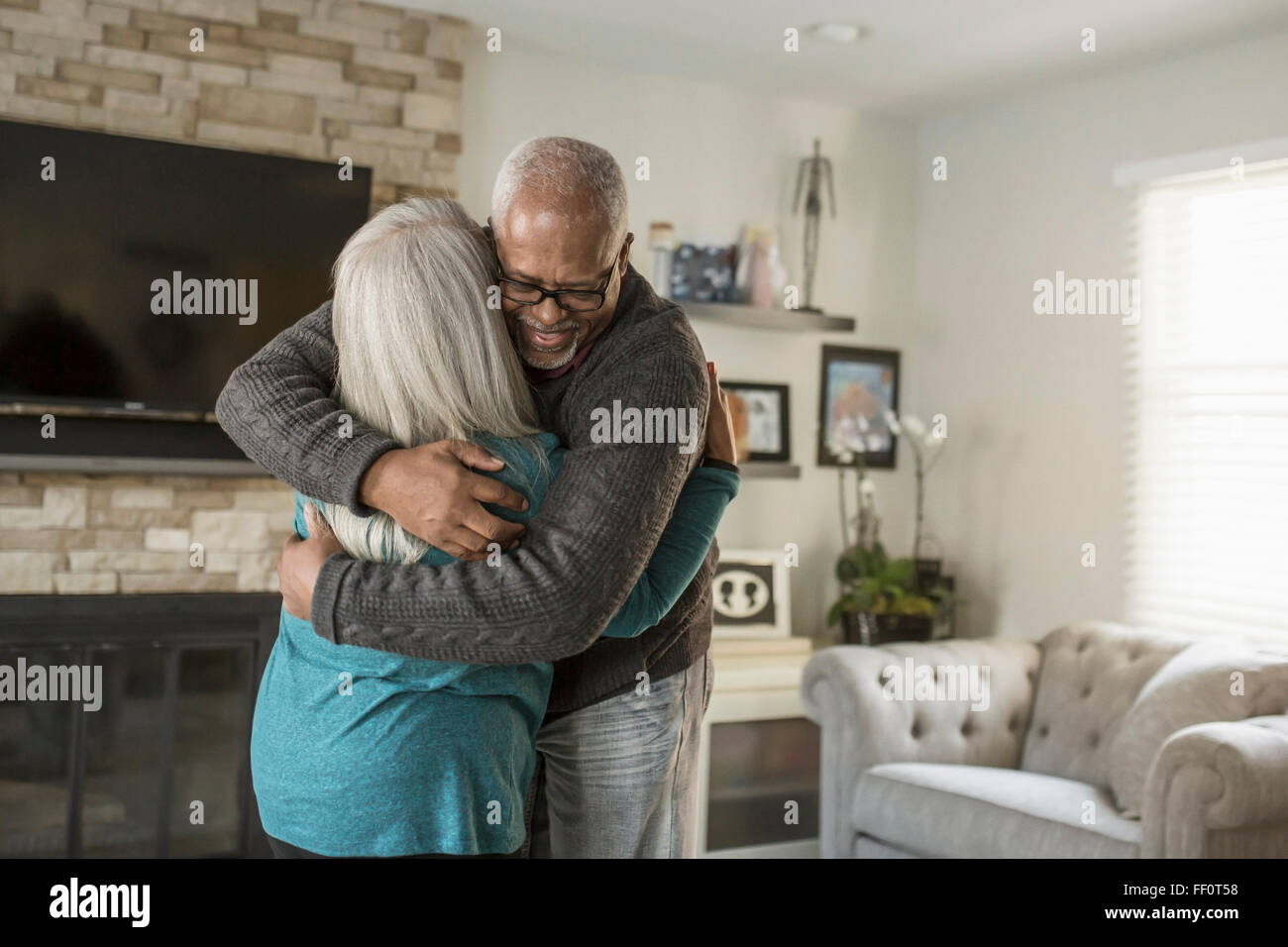 Älteres Ehepaar im Wohnzimmer umarmt Stockfoto