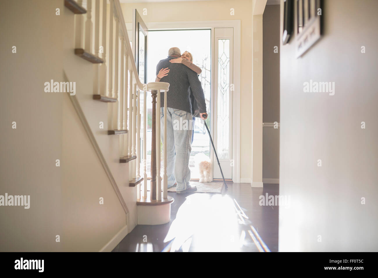 Mann umarmt Besucher in der Haustür Stockfoto