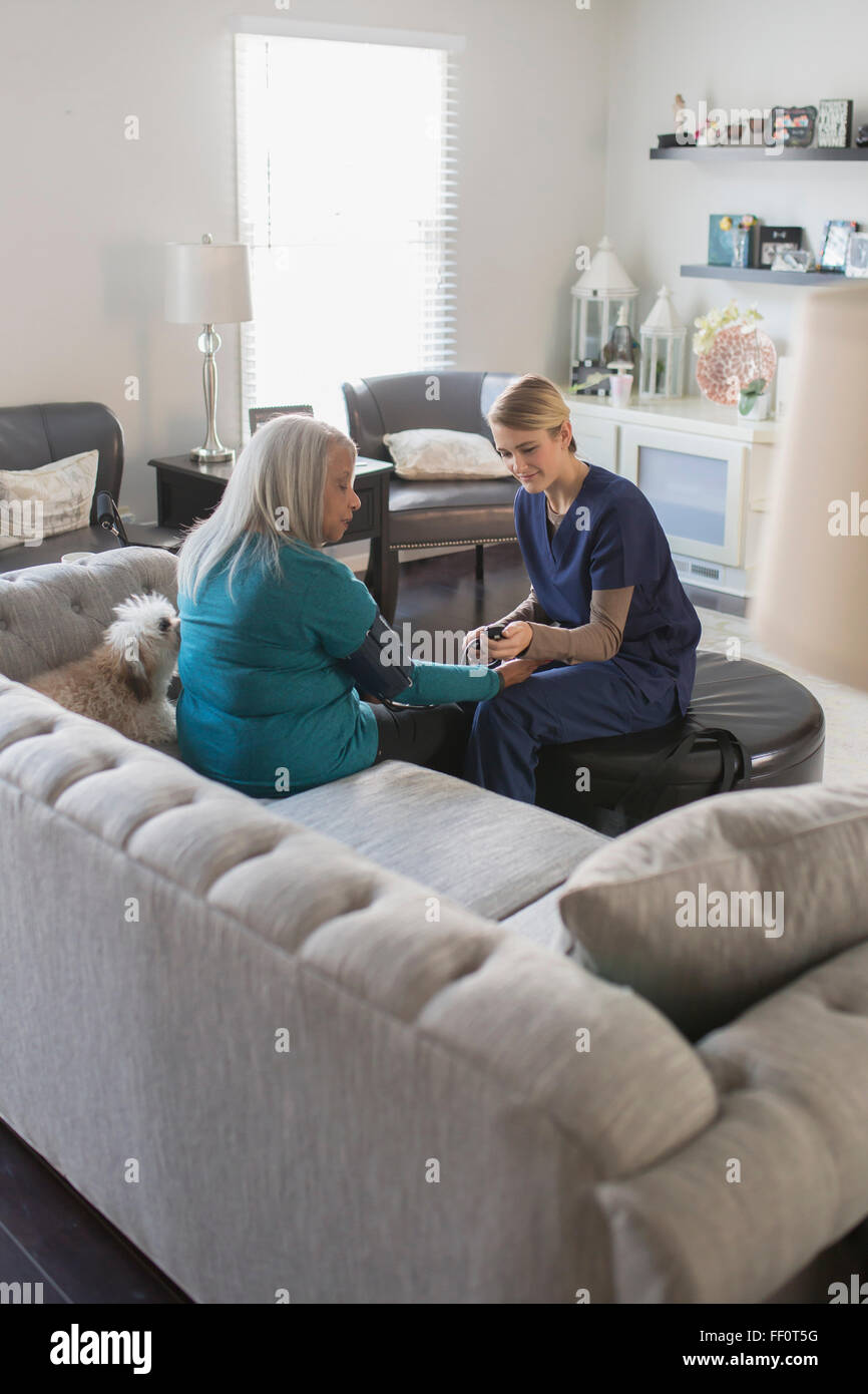Krankenschwester, die die Patienten Blutdruckmessung im Wohnzimmer Stockfoto