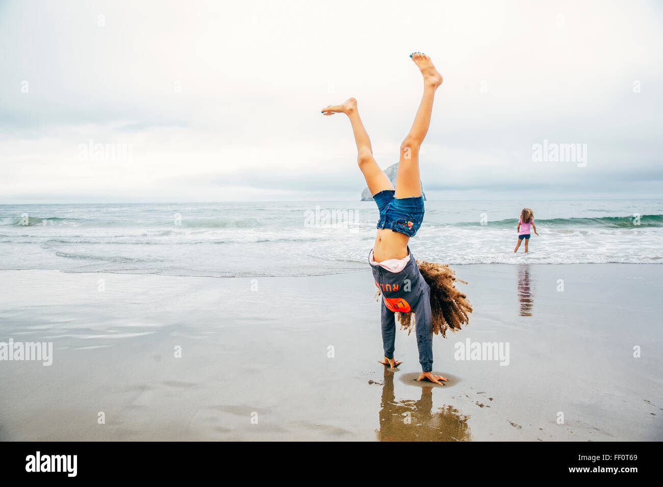 Gemischte Rassen Mädchen tun Handstand am Strand Stockfoto