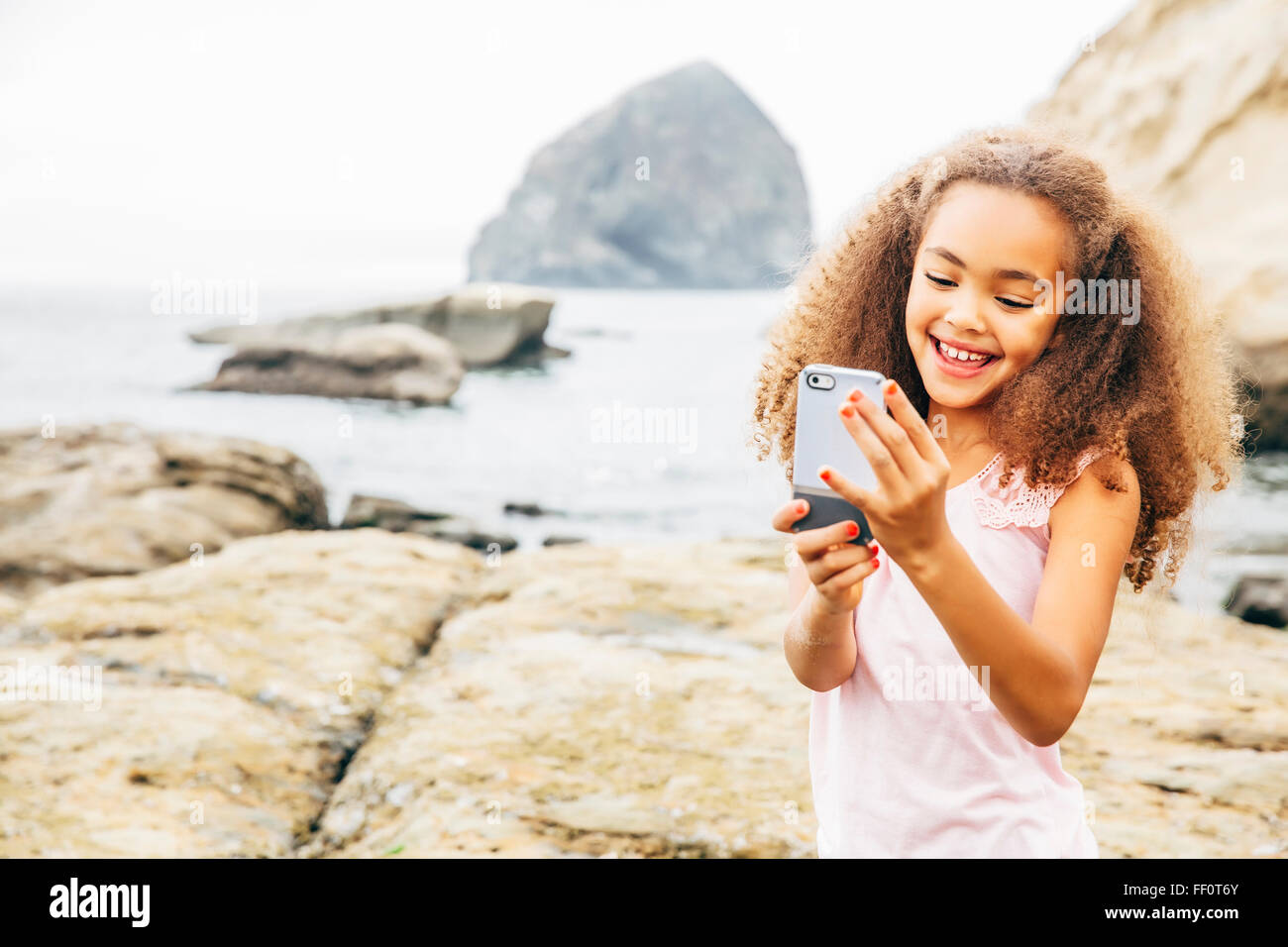 Gemischte Rassen Mädchen mit Handy am Strand Stockfoto