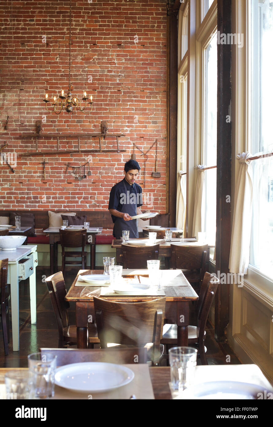 Ein Restaurant-Mitarbeiter deckt den Tisch in einem Restaurant nach dem Mittagessen Gottesdienst. Stockfoto