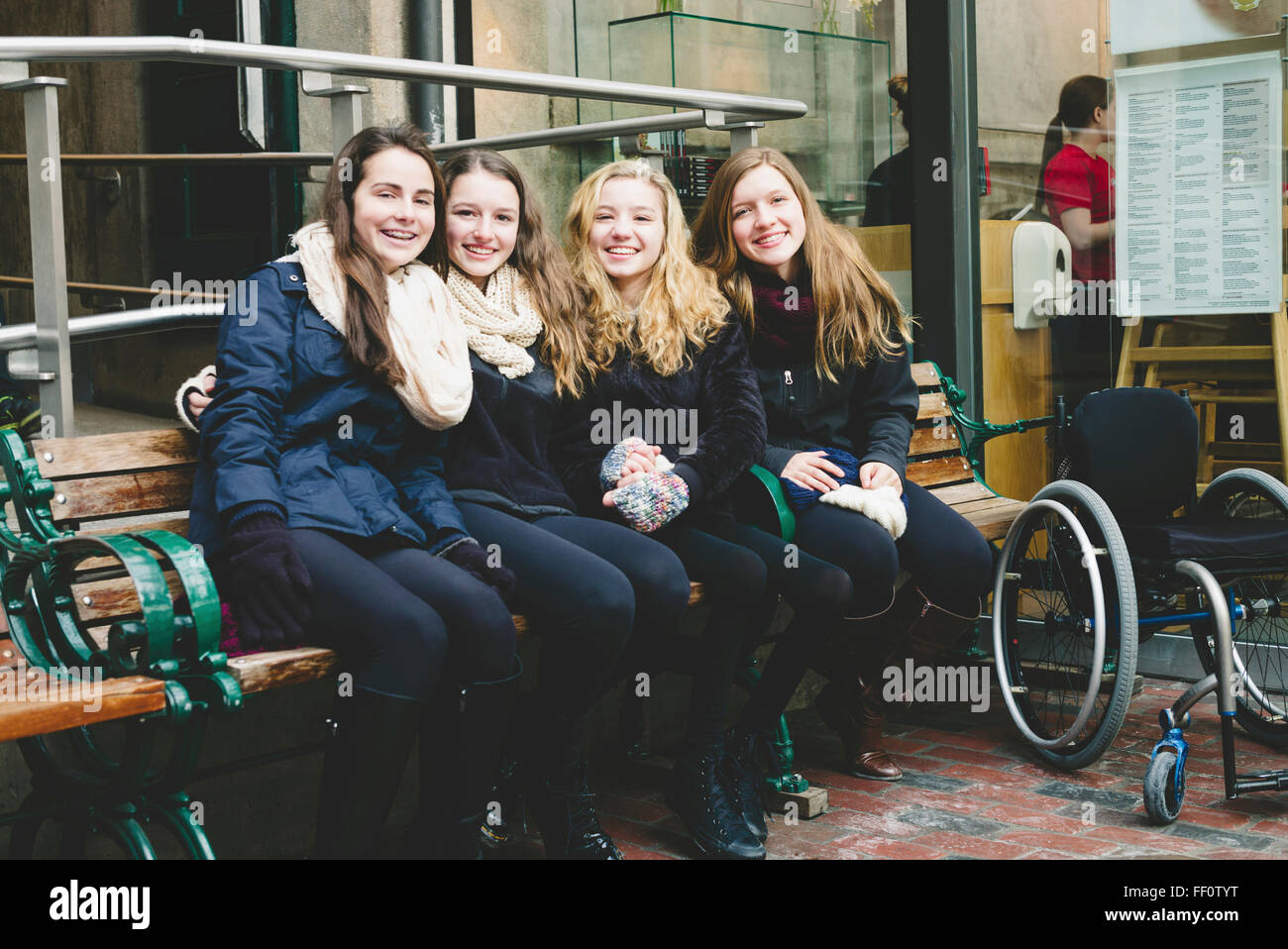 Mädchen im Teenageralter lächelnd auf Bank Stockfoto