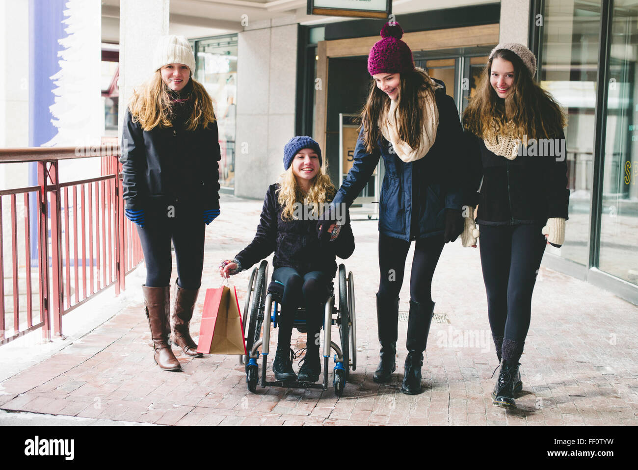 Mädchen zu Fuß und mit Rollstuhl auf Bürgersteig Stockfoto