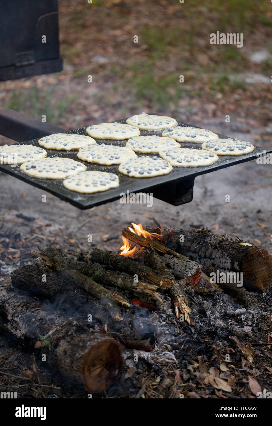 Ein Dutzend Heidelbeer-Pfannkuchen kochen auf dem Grill über dem Lagerfeuer. Stockfoto