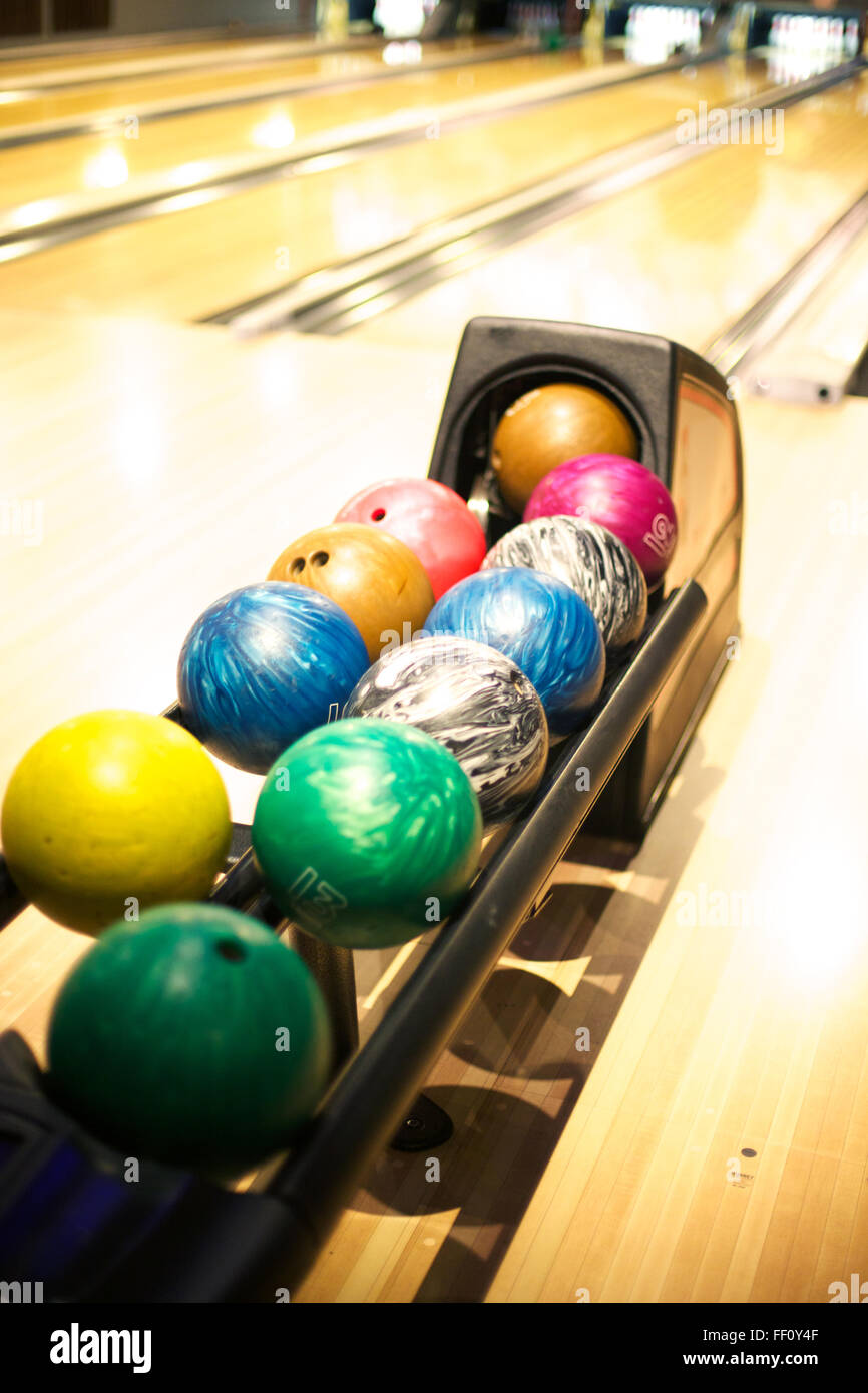 Eine bunte Auswahl an Bowling-Kugeln aufgereiht am ball Maschine in einer Bowlingbahn. Stockfoto