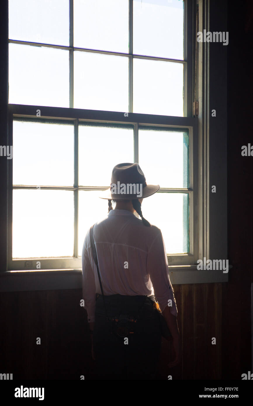 Eine Frau mit einem Hut schaut ruhig aus dem Fenster. Stockfoto