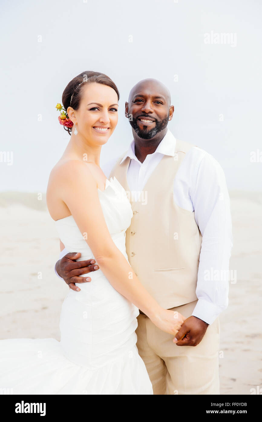 Brautpaar am Strand umarmt Stockfoto