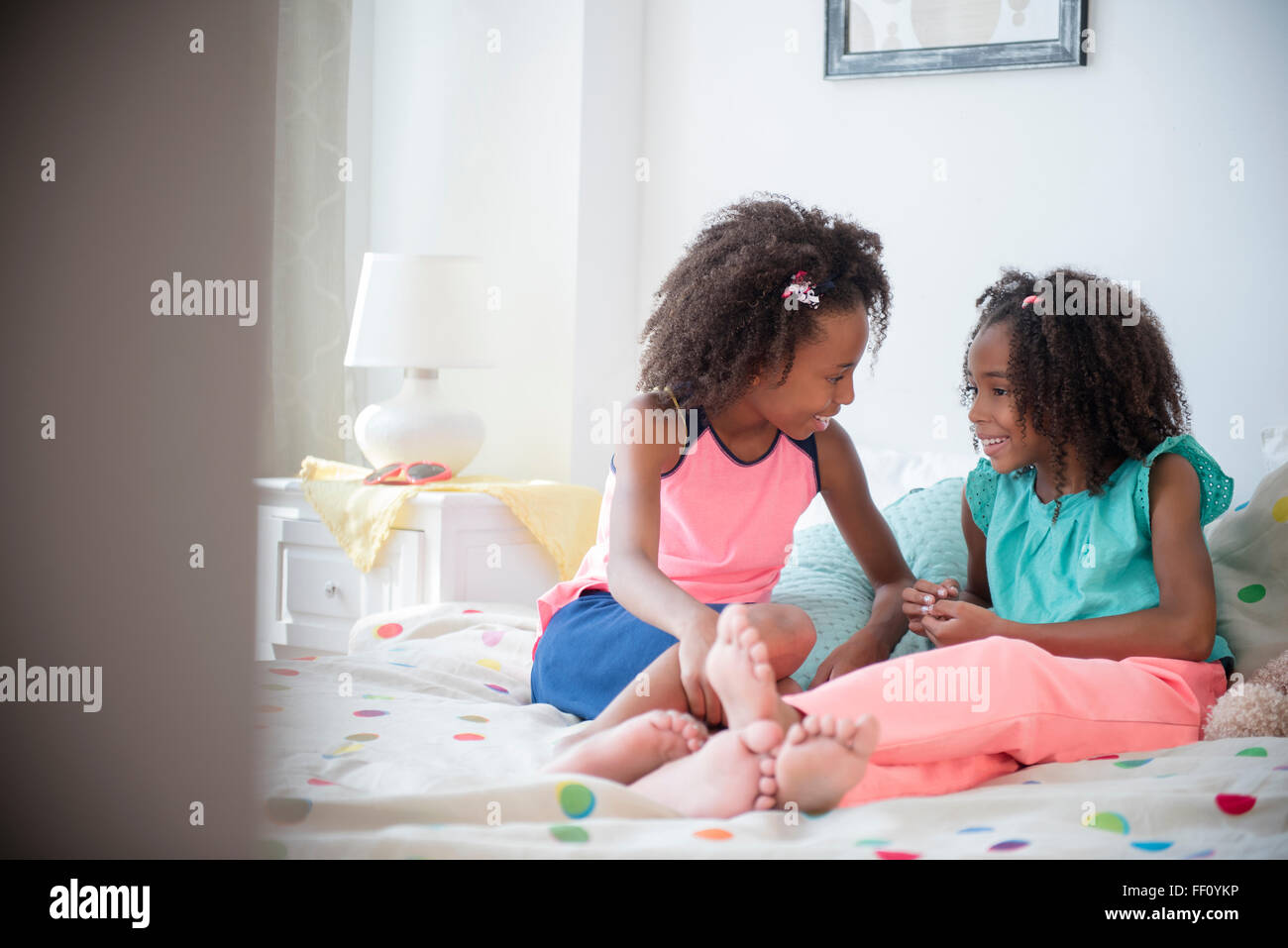 Gemischte Rassen Schwestern sprechen auf Bett Stockfoto
