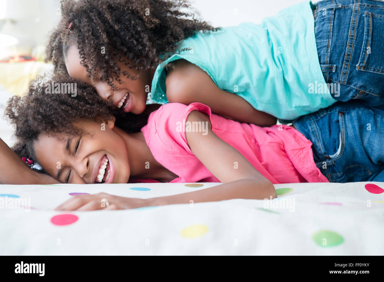 Gemischte Rassen Schwestern spielen auf Bett Stockfoto