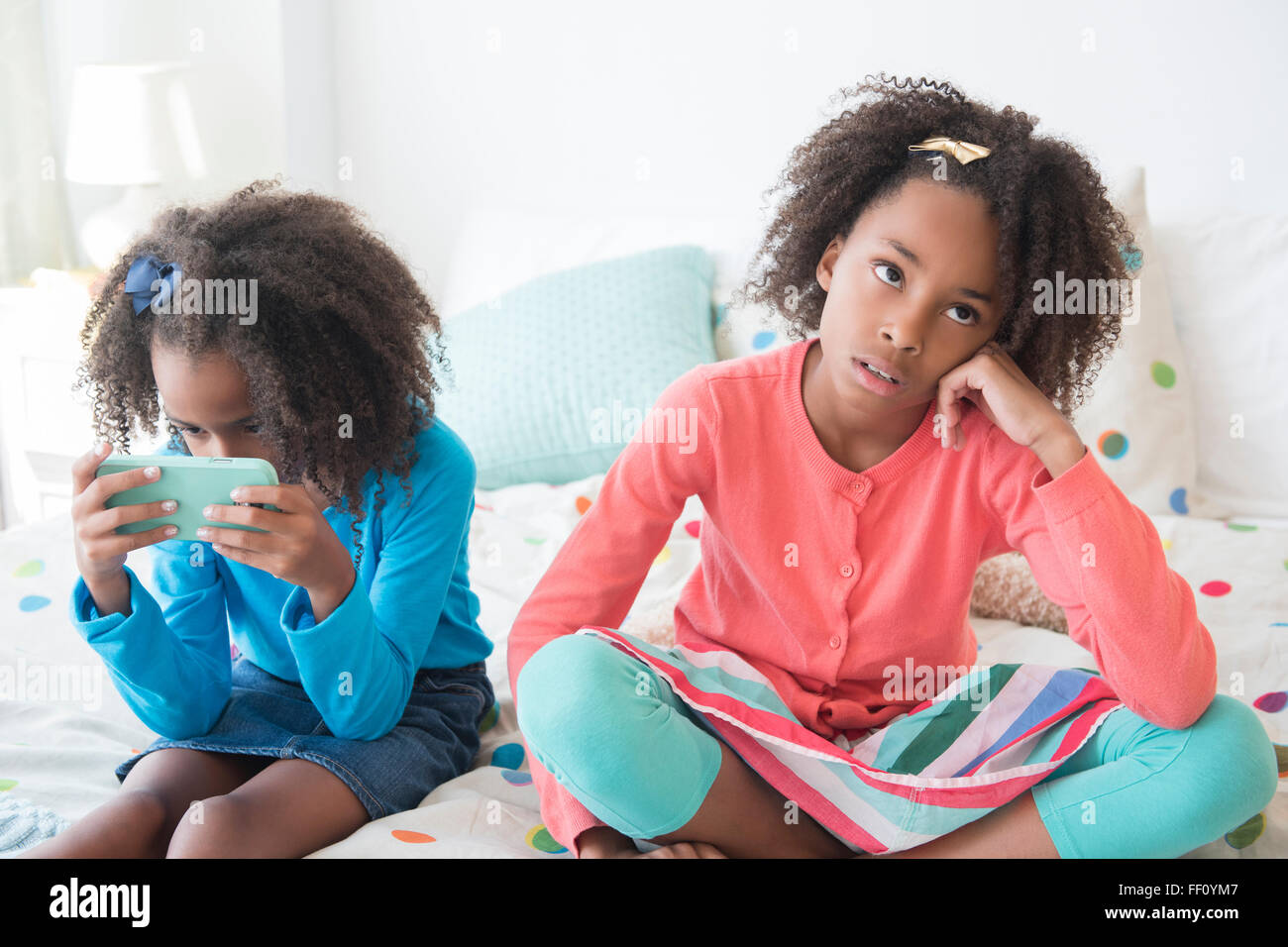 Gelangweilt Mischlinge Mädchen sitzen auf Bett Stockfoto