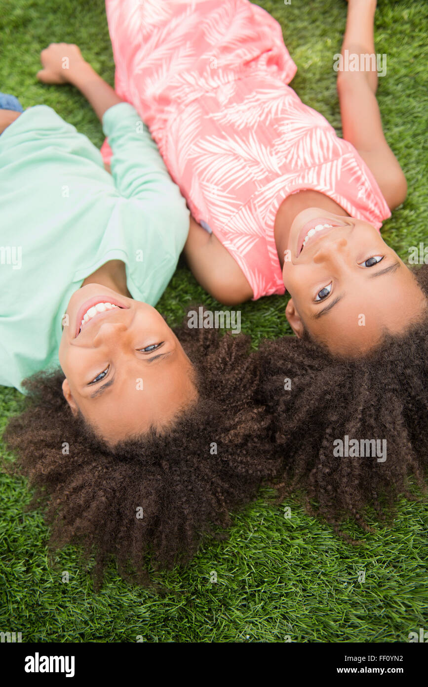 Gemischte Rassen Schwestern Verlegung in Rasen Stockfoto