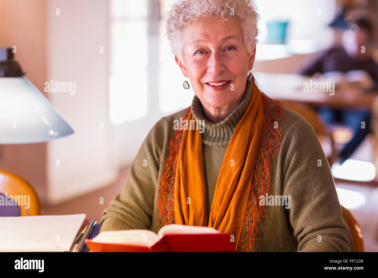 Ältere Mischlinge Woman Holding Buch in Bibliothek Stockfoto